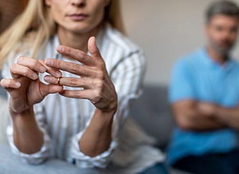 Woman taking off her wedding band, symbolizing marital separation - Aminu Law Firm, PLLC