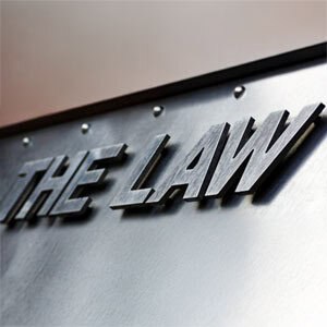 A close-up view of a metallic sign with the words 'THE LAW' prominently displayed in bold, raised letters - Aminu Law Firm, PLLC