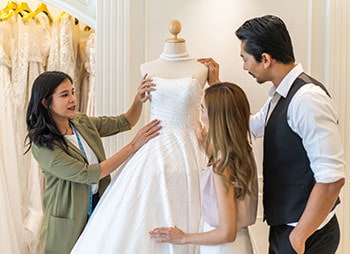 Bride and groom consulting with a wedding dress designer in a boutique - Aminu Law Firm, PLLC