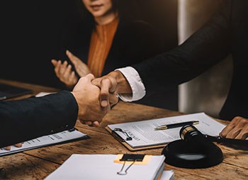 Lawyer and client shaking hands after a successful legal settlement - Aminu Law Firm, PLLC