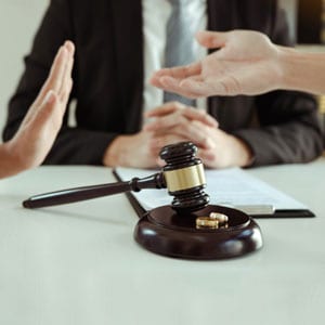 Divorce proceedings with gavel, rings, and disagreement between spouses in a law office - Aminu Law Firm, PLLC